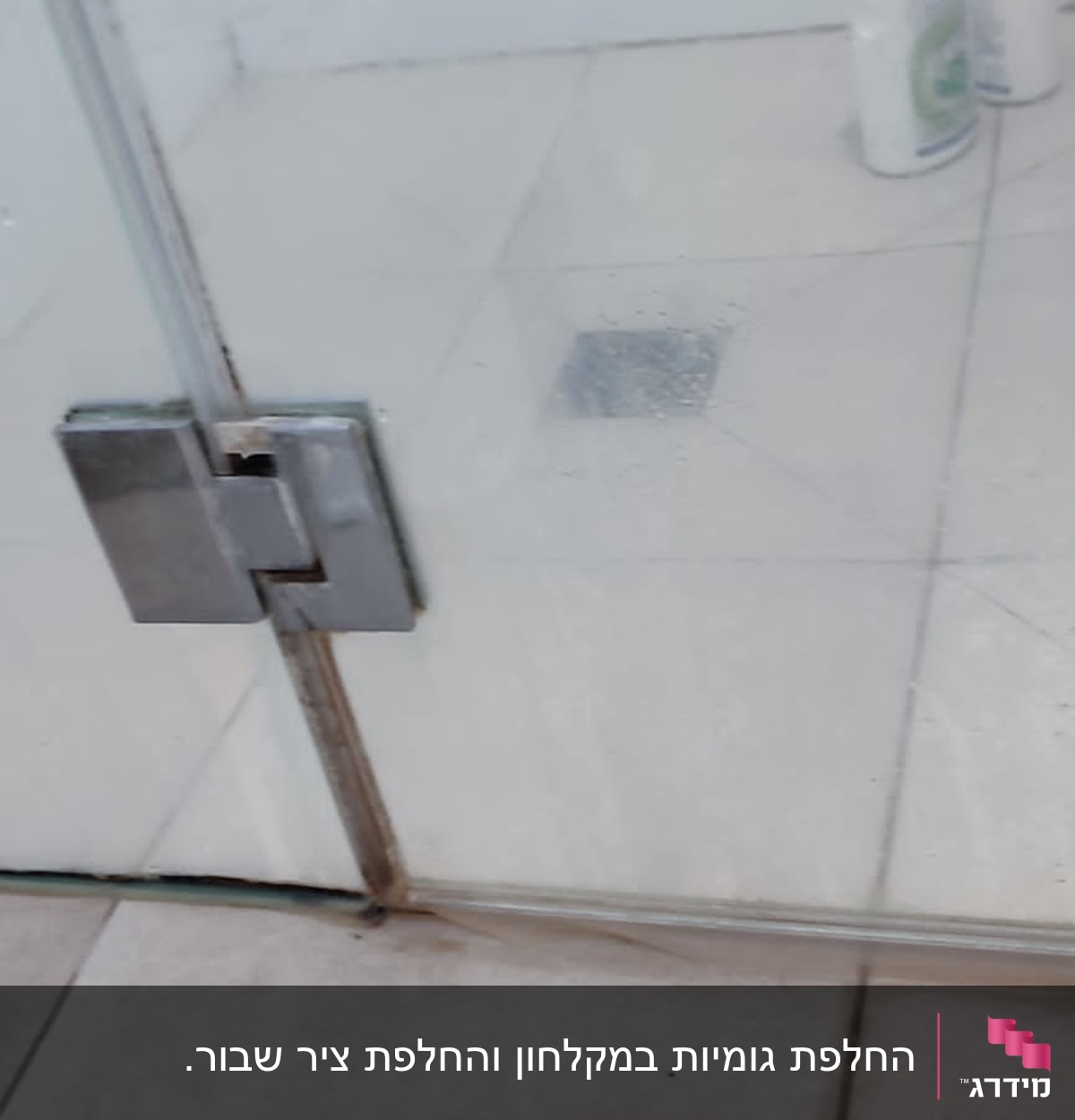 דלת זכוכית למקלחת עם בקבוקי שמפו על הרצפה